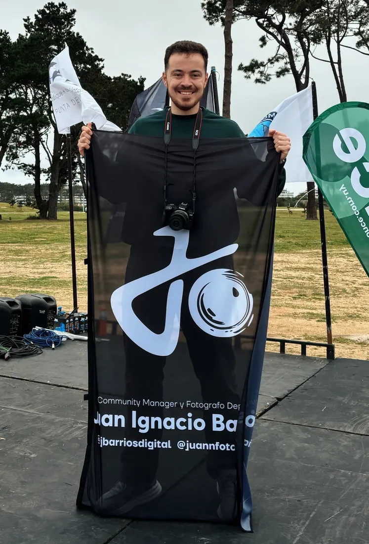 Juan Barrios con su cámara y su bandera en el escenario de una carrera