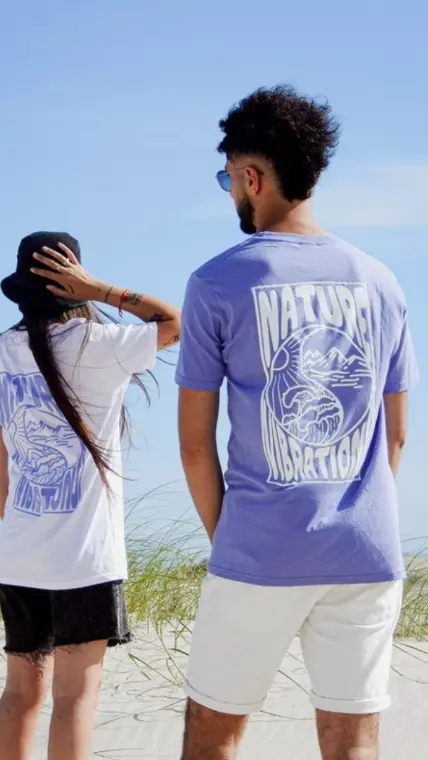 Pareja de espaldas con remeras Ride & Shine en la playa