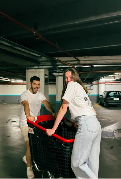 Pareja con remeras Ride & Shine jugando con un carrito